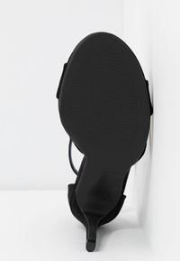 Escarpin en suède noir avec une semelle lisse et un talon fin. Dispose d'une semelle en caoutchouc texturé pour une meilleure adhérence et d'un design minimaliste.