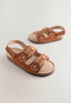 Sandalias de ante marrón con bordado floral, que cuentan con dos correas ajustables, un soporte para el talón trasero y una suela de goma texturizada.