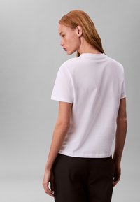 Tricou alb din bumbac cu croială lejeră, mâneci scurte și tiv drept. Textură netedă, detalii minime la cusături și decolteu rotund.