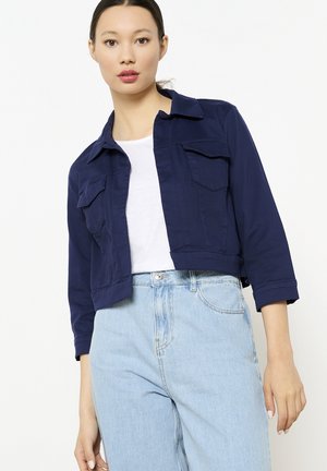 Veste courte marine en tissu léger, dotée de deux poches poitrine, d'un col pointu et de manches trois-quarts.