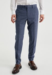 Tailored blue checkered trousers with a smooth texture, fitted design, and flat front; paired with brown leather loafers.