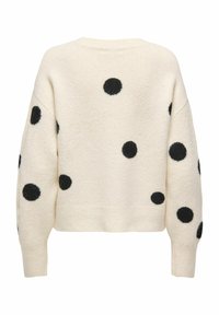 Pull couleur crème avec pois noirs duveteux. Coupe courte, poignets et ourlet côtelés. Texture douce, coupe décontractée.