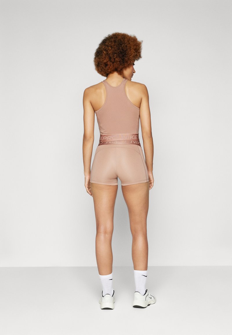 Top atletico beige e pantaloni corti realizzati in un tessuto morbido, caratterizzati da un design con schiena a corsetto e una vita elastica con un accento del logo del marchio.