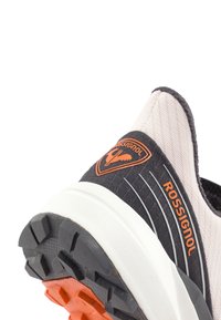Černá a růžová atletická bota s texturovaným textilním svrškem, s oranžovým logem, bílou mezipodešví a vzorovanou černou gumovou podrážkou.