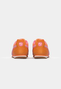 Sneaker mit einem Obermaterial aus beige Wildleder, pinken und lila Akzenten, gepolstertem Kragen und weißer Sohle. Mit einem Logo an der Ferse und an der Seite.