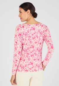 Camicia a maniche lunghe con motivo floreale in rosa e crema, tessuto morbido, scollatura a girocollo e design aderente. Presenta maniche senza cuciture e orlo curvo.