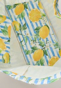 Reusable tote bag featuring a lemon and flower pattern on a blue and white striped background. Made of fabric with a soft texture.