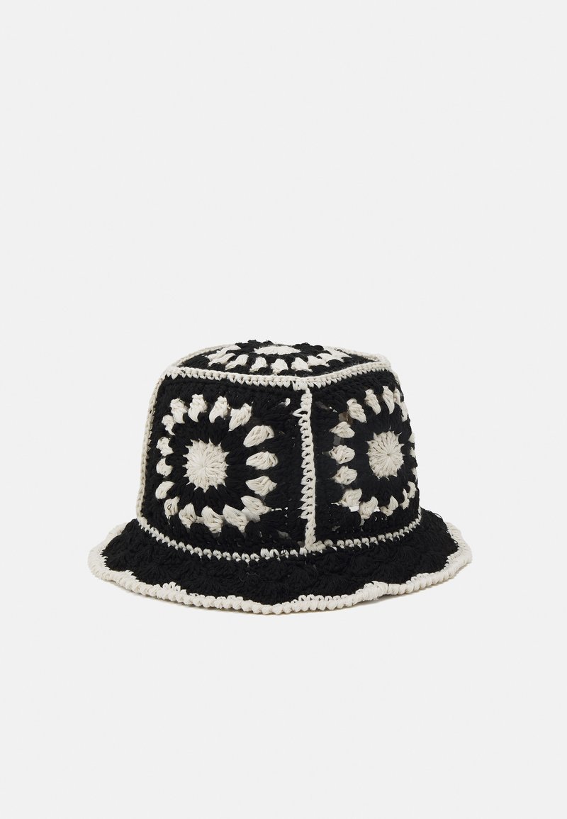 Chapeau seau au crochet en noir et blanc avec des motifs circulaires. Forme structurée avec un large bord et une finition texturée.