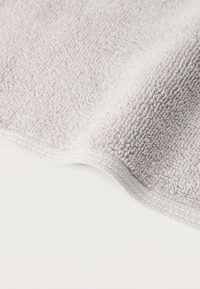 Κλείσιμο ματιού σε απαλό, ανοιχτό γκρι τριχωτό ύφασμα με υφή από θηλιές και ραμμένη επένδυση κατά μήκος της άκρης.