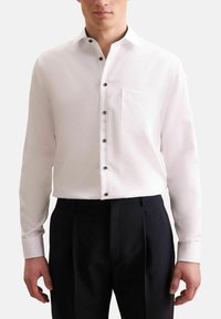 Witte lange mouwen shirt met een klassieke kraag, zwarte knopen en een borstzak, gecombineerd met zwarte broeken, die een gladde textuur tonen.