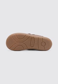 Suela de zapato de goma marrón con un patrón de agarre texturizado, que presenta un diseño hexagonal y detalles de logo. Bordes lisos y forma redondeada.
