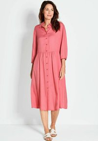 Abito rosa, con bottoni, di lunghezza media, con vita plissettata e maniche a tre quarti. Tessuto morbido, vestibilità rilassata e design semplice.