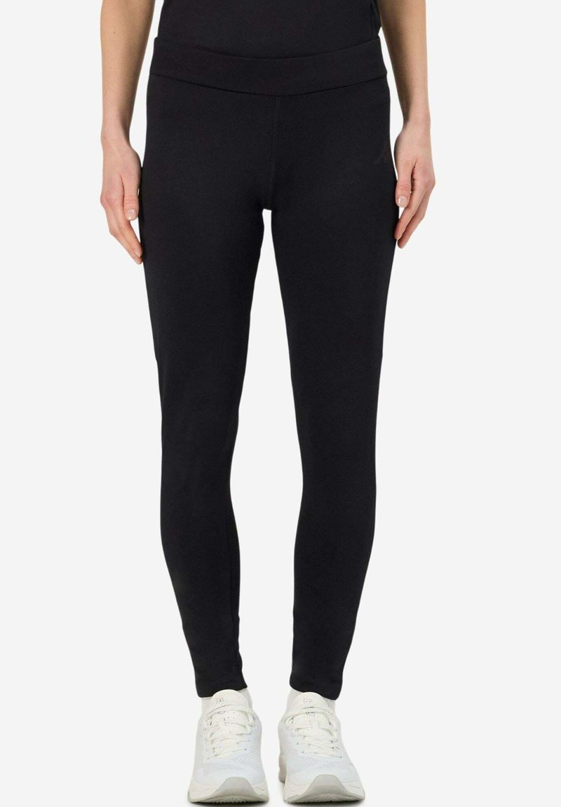 Leggings neri realizzati in tessuto elastico, con vita alta e finitura liscia. Abbinati a scarpe da ginnastica bianche.
