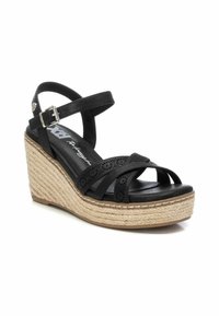 Sandalias de cuña negras con suela de yute trenzado, con correas perforadas y una hebilla ajustable en el tobillo. Material sintético suave.