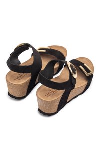 Sandali platform in suede nero con base in sughero, ampie cinghie con fibbie dorate e suola in gomma testurizzata per una buona aderenza.