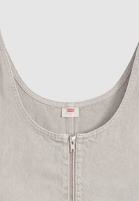 Haut sans manches gris clair avec fermeture éclair argentée à l'avant et étiquette de la marque Levi's à l'intérieur de l'encolure.