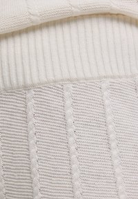 Pull en tricot blanc avec un col à côtes, des rayures texturées et des détails en ajours, offrant une apparence douce et chaleureuse.
