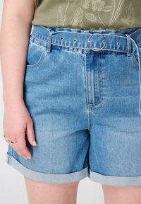 Lichte blauwe denim shorts met een opgerolde zoom, een zilveren ronde riemgesp en voorzakken. Geweven materiaal met een vervaagd uiterlijk.