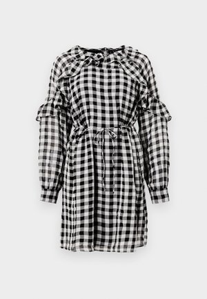 Musta-valkoinen ruudullinen mekko, jossa on röyhelökaulus ja -hihoja, kiristetty vyötärö nauhalla sekä pitkät läpikuultavat hihat.