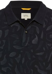 Polo shirt in donker marineblauw, met een subtiele bladpatroonstructuur, een effen kraag en een gouden knoopaccent, gelabeld "camel active" aan de binnenkant.