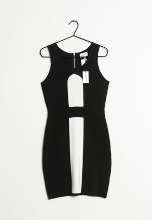 Robe noire moulante sans manches avec panneaux verticaux blancs au centre devant, encolure ronde, fermeture éclair au dos, suspendue sur un cintre noir avec une étiquette MILLY.