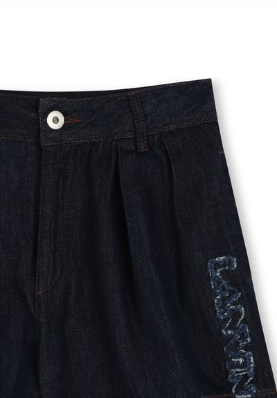 Shorts en denim foncé avec un devant plissé, dotés d'une fermeture à bouton argenté et d'un texte brodé en bleu clair sur le côté.