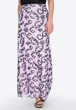 Gonna lunga lavanda con motivo a spirale floreale nero, indossata con sandali neri con cinturini e una maglia nera.