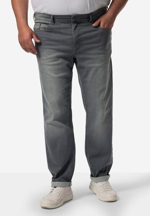 Pantalones de mezclilla gris con un diseño de pierna recta. Presentan un estilo clásico de cinco bolsillos y dobladillos acampanados, combinados con zapatillas deportivas blancas.