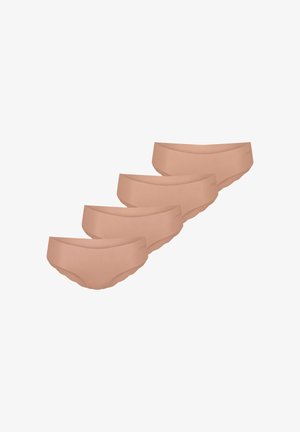 Femme aux cheveux bouclés portant un soutien-gorge sans couture couleur chair et une lingerie assortie, posant avec le bras gauche croisé sur le torse devant un fond uni.