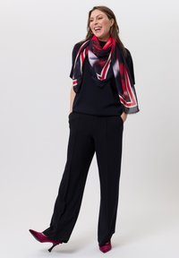 Navy top with short sleeves, black wide-leg pants, and a printed scarf in red, black, and white. Pink heels with a pointy toe.