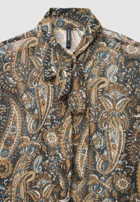 Sheer, black blouse with ornate paisley pattern in brown, blue, and cream. Features a tie neck, blending intricate floral and leaf designs.