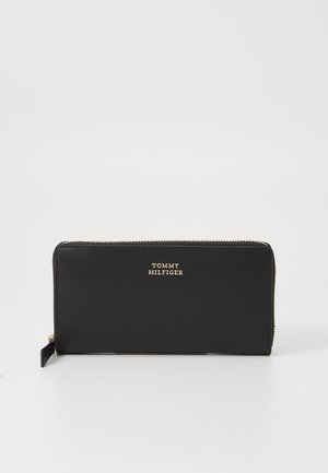 Černá kožená peněženka se zlatými prvky. Obsahuje zipové zapínání a ražené logo značky. Hladký povrch a obdélníkový tvar.