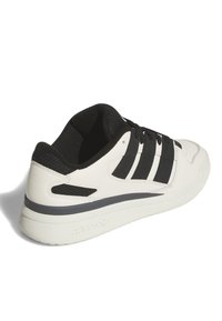 Sneaker bianca con strisce nere, dettagli in mesh, colletto imbottito nero e una striscia grigia lungo la suola. Suola in gomma strutturata.