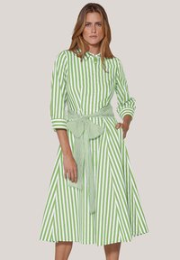 Grün und weiß gestreiftes Hemdkleid mit durchgehender Knopfleiste, umgeschlagenen Ärmel und einem passenden Bindegürtel in der Taille. Ausgestellter Rock.