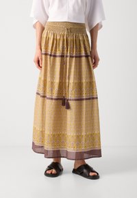 Maxirock in Gelb mit Blumenmustern, smocktem Bund und Kordelzug, mit einem kontrastierenden braunen Saum und einer strukturierten Oberfläche.