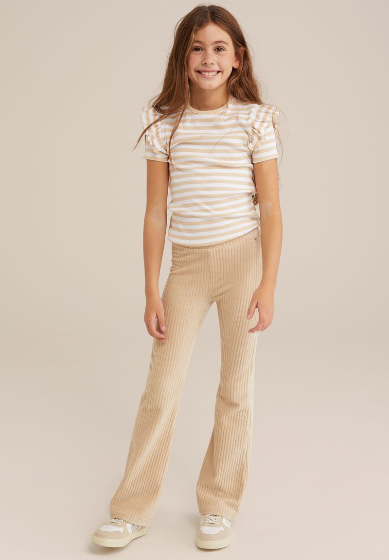 Striped short-sleeve top with puff shoulders, beige and white; paired with beige ribbed flared pants, textured fabric, and casual sneakers.