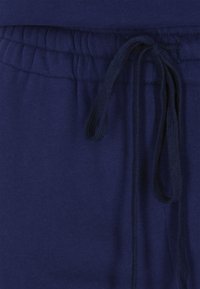 Pantalones de chándal azul marino con una cintura flexible, que cuentan con un cordón para un ajuste ajustable y una superficie suave y texturizada.