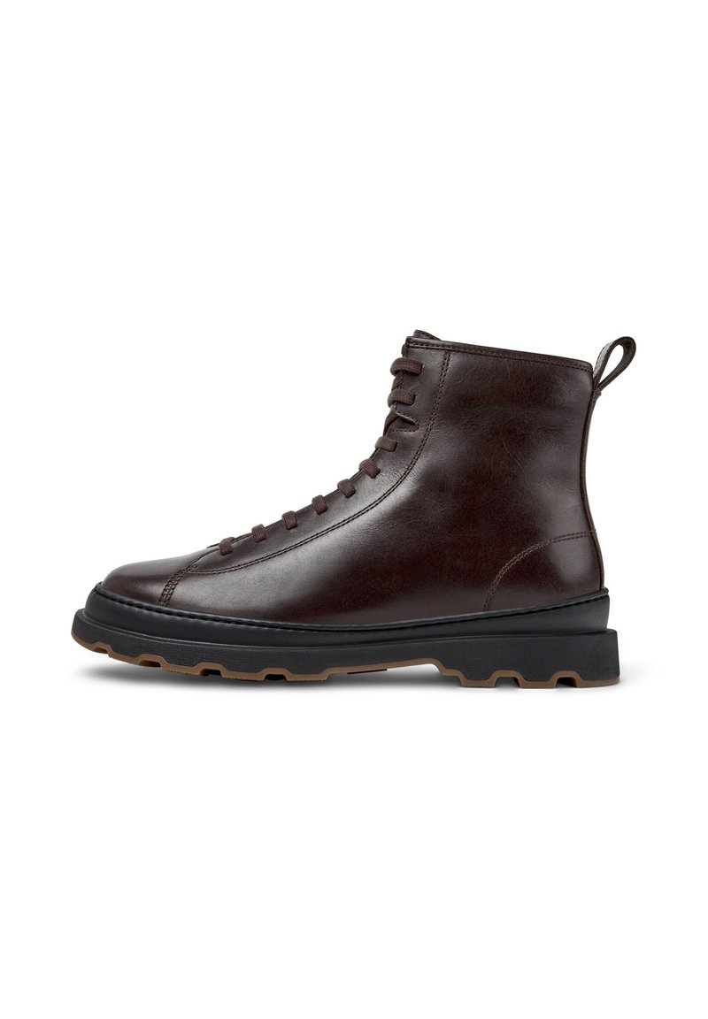 Bota de tobillo de cuero marrón con un acabado suave, punta redonda y cordones en la parte delantera. Presenta una suela de goma negra contrastante con un agarre texturizado.