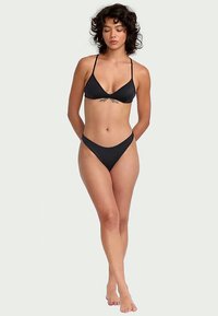 Bikini noir avec un haut triangulaire à fines bretelles et une coupe classique en bas. Texture lisse, design minimal et matériau léger.