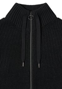 Černý žebrovaný svetr s klínovým zapínáním na zip a vysokým límcem, vybavený šňůrkami a kovovým zipem. Texturovaný, pohodlný materiál s jemným leskem.