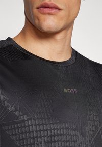 Musthave mustriks T-särk musta värviga, millel on tekstureeritud geomeetrilised mustrid. Omab ümmargust kaelust ja "BOSS" logo õrnalt gradient värviga.