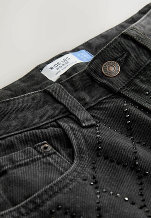 Wide-leg jeans in dark gray denim with black bead embellishments and a brass button. Features a mid-rise waist and five-pocket design.