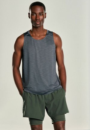 Débardeur de sport gris avec un motif texturé, associé à un short vert olive. Le débardeur présente des bretelles larges et une coupe décontractée.