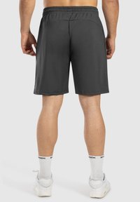 Dunkelgraue Sportshorts mit elastischem Bund, glattem Stoff und zwei Seitentaschen. Sie haben einen knielangen Schnitt und eine minimalistische Gestaltung.