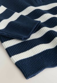 Gestreifter Strickstoff in Marineblau und Creme, mit gerippter Textur und umgeschlagenem Ärmel, der abwechselnd breite und schmale Streifen zeigt.