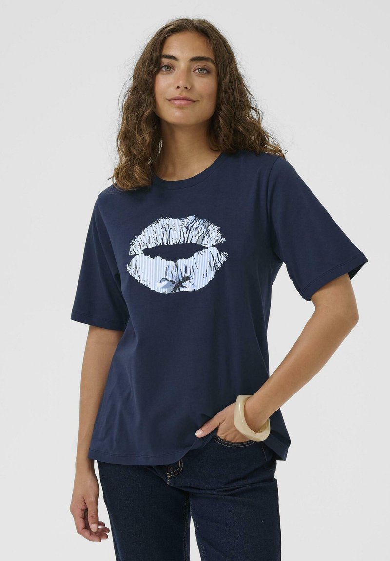 Navyblaue Baumwoll-T-Shirt mit einem weißen Lippen-Graphic in der Mitte. Kurze Ärmel, lockere Passform, Rundhalsausschnitt. Glatte Textur.