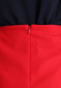 Robe bicolore avec un haut bleu marine et un bas rouge. Dotée d'une fermeture éclair dissimulée dans le dos. Tissu lisse avec des coutures nettes.
