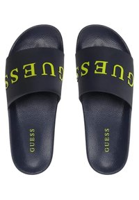 Navyblauwe slippers met een gladde textuur, met een brede zwarte band die in het midden is bedrukt met het gele "GUESS"-logo.
