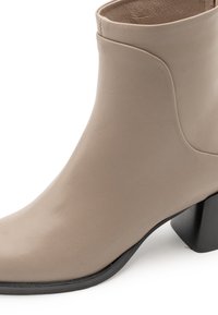 Stivale alla caviglia beige in pelle con punta arrotondata e tacco spesso nero. Texture liscia con dettagli di cucitura minimi.