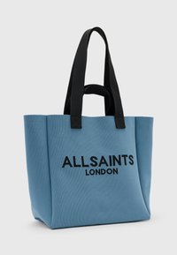 Niebieska torba na ramię z czarnymi uchwytami, z wytłoczonym napisem "ALLSAINTS LONDON". Wykonana z teksturowanej tkaniny o zdefiniowanym kształcie.